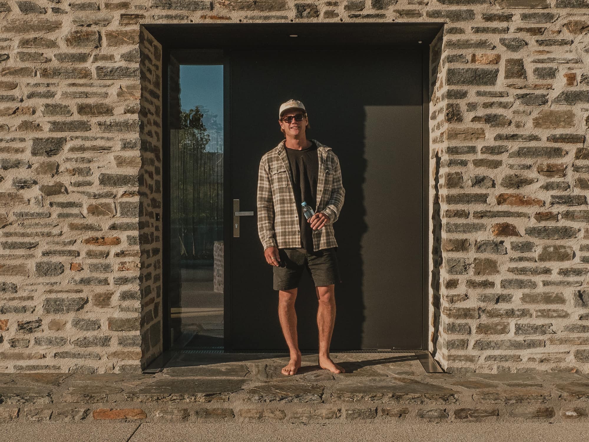 Schist entry and black steel door in evening light