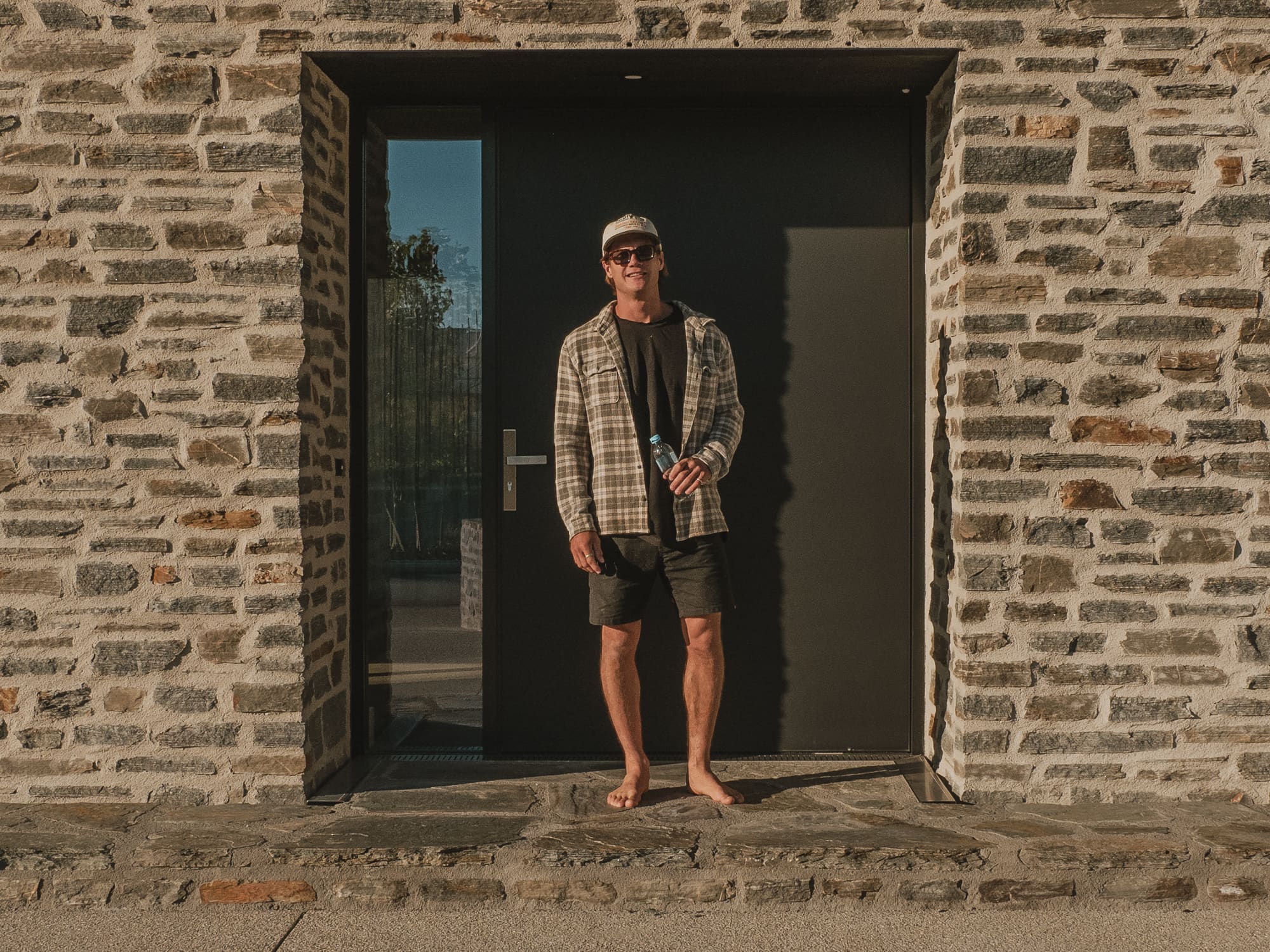 Central Otago schist entrance with a black steel door in evening light